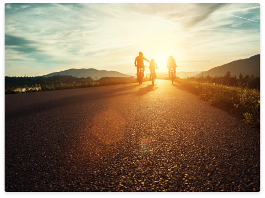 family riding bikes into sunset