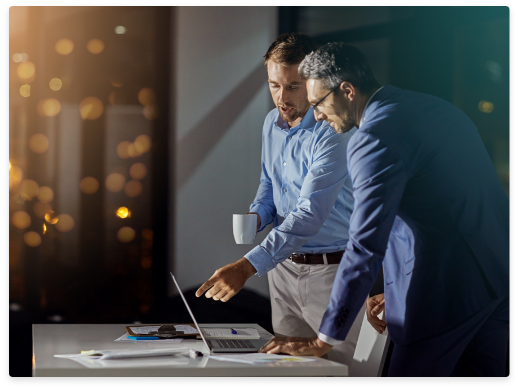 two guys standing in front of laptop